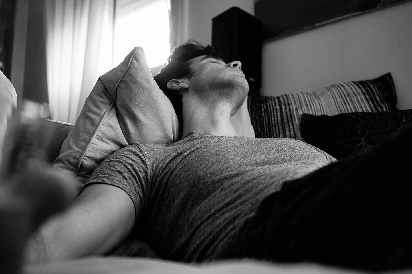 a grayscale photo of a man sleeping on sofa