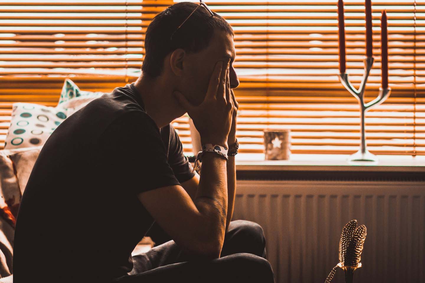 Man sitting on chair rubbing his eyes.