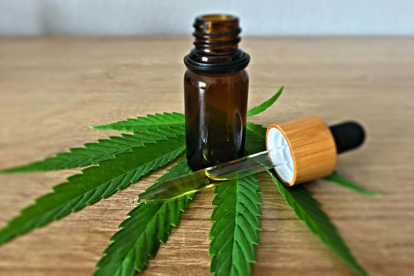 Small brown jar and dropper sitting on a hemp leaf