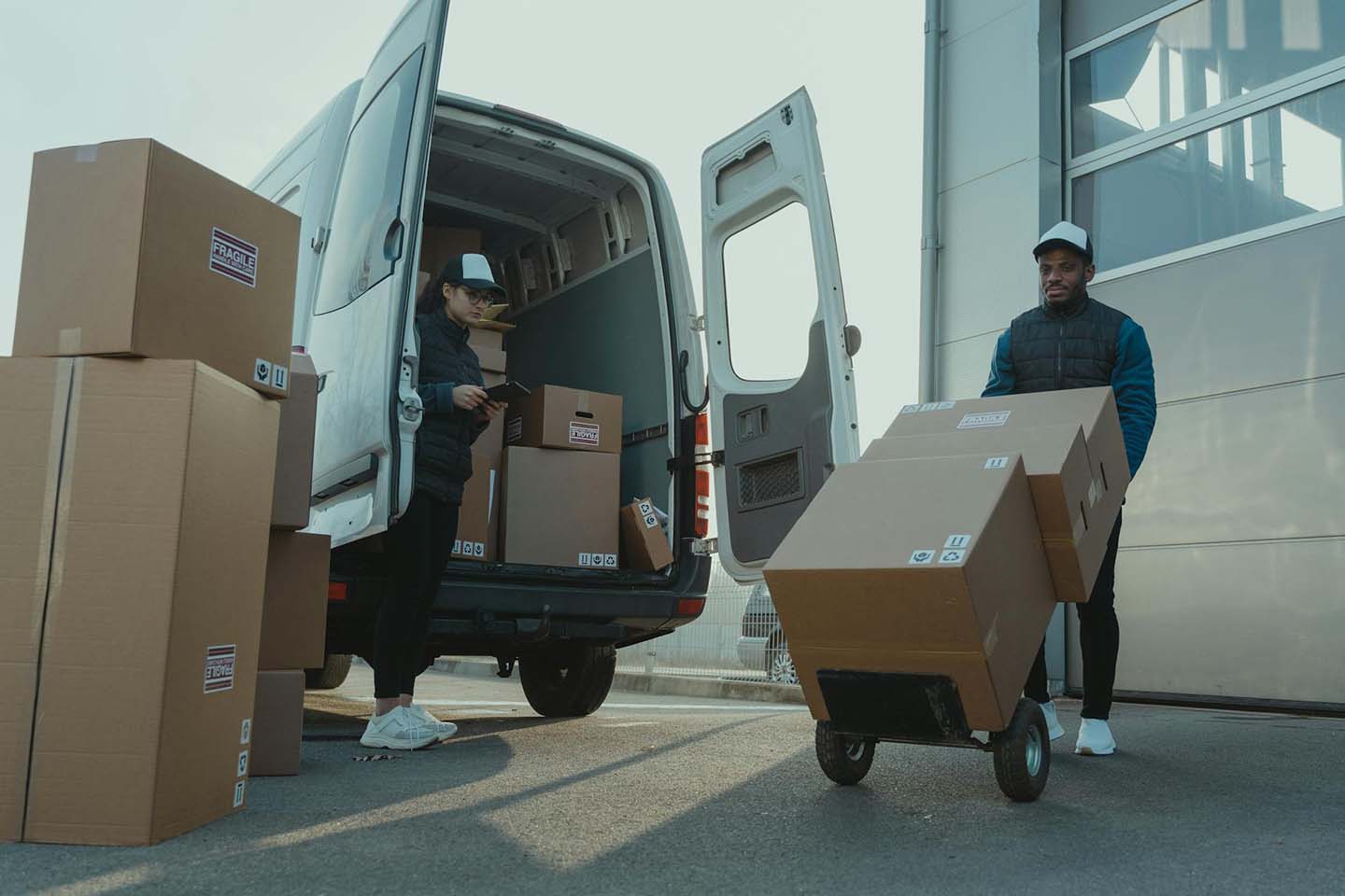 a man and a woman working for a delivery company getting several boxes from a truck