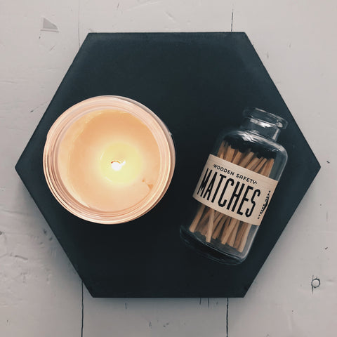 Lit Nomad Wax Candle and glass bottle wood matches on hexagon tile