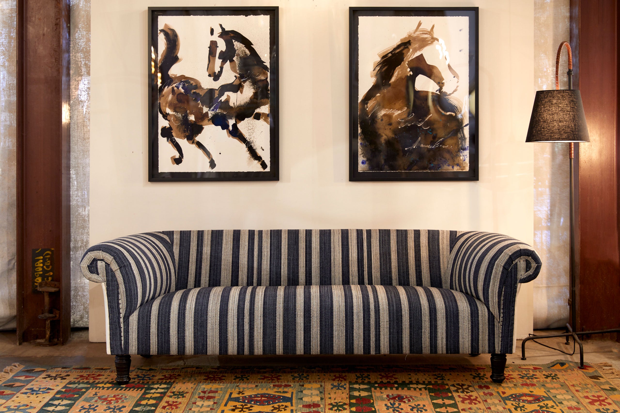 sofa in striped fabric with two painting on the wall behind the sofa