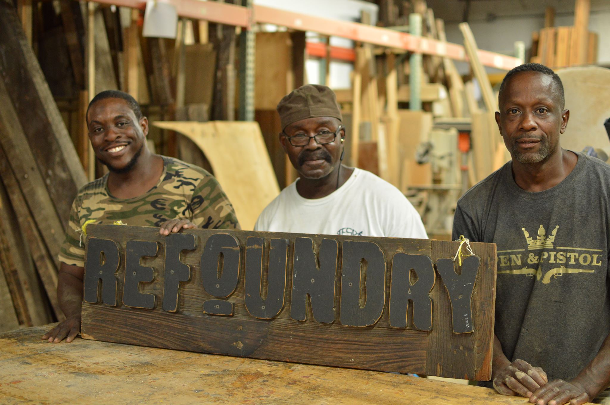 three craftsmen holding a refoundery sign