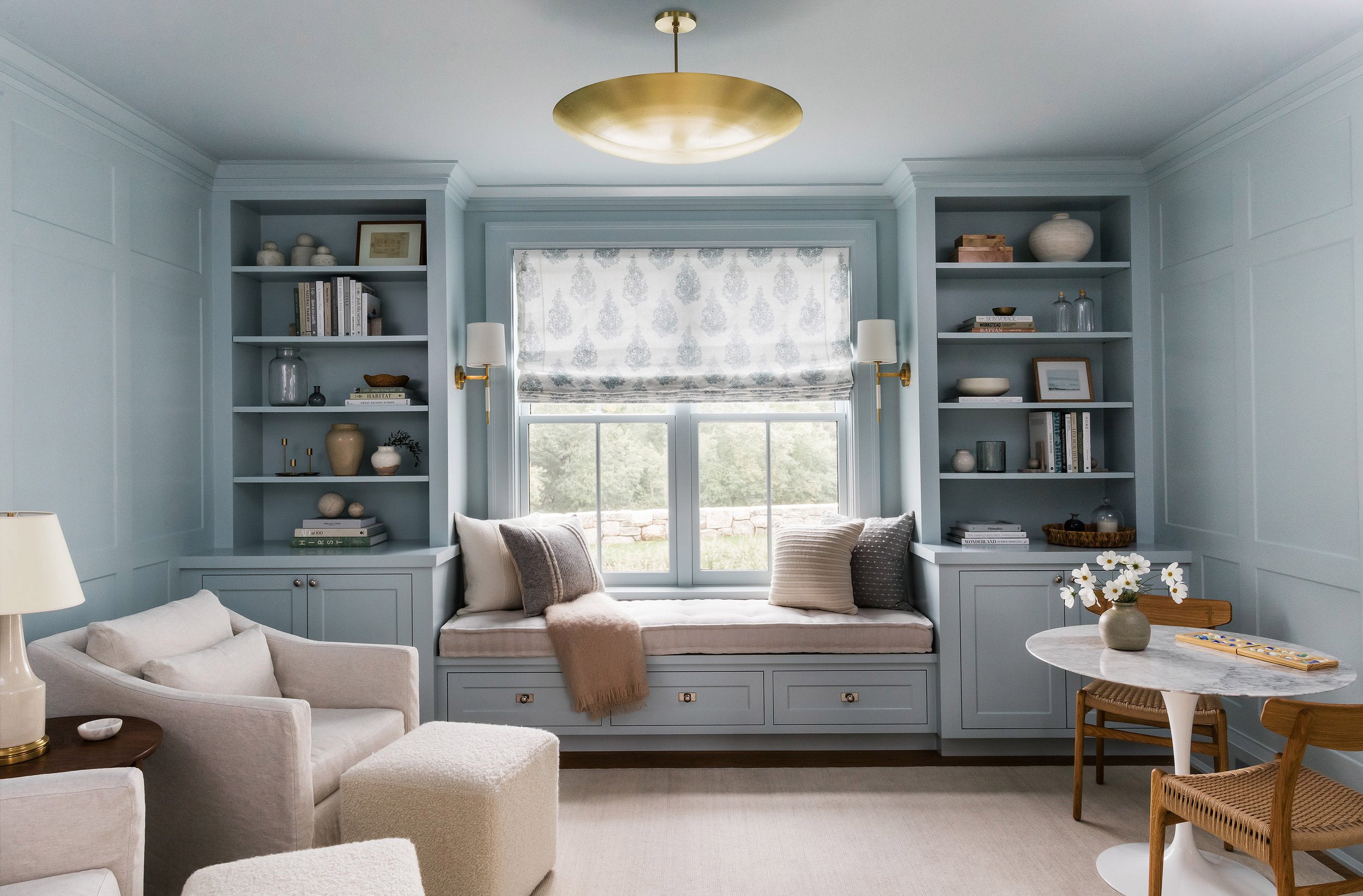 interior with arm chair and ottoman. Window with bench and a small bistro table.