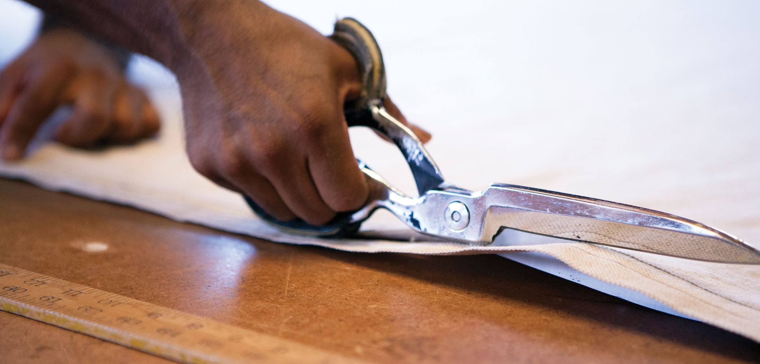 Craftsman cutting fabric with scissors