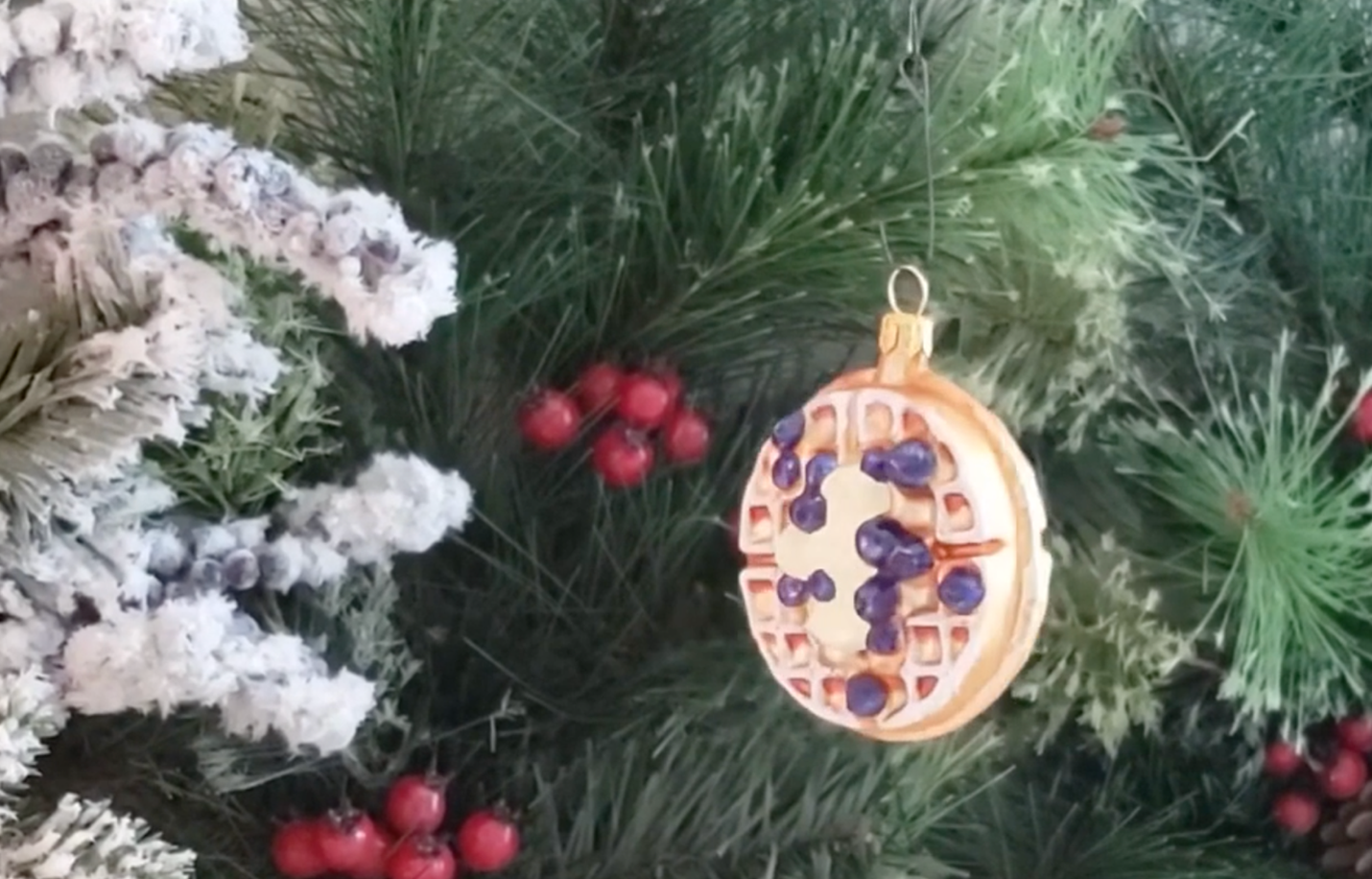 a christmas ornament of a waffle with blueberries hangs on a tree