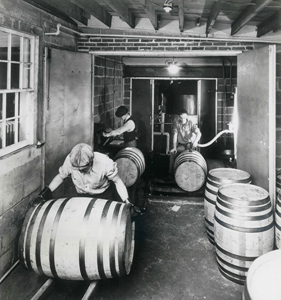 people rolling barrels in black and white