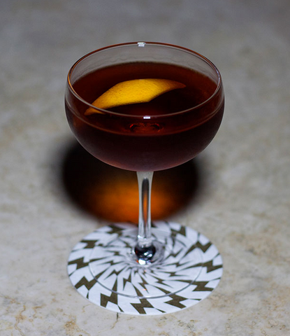 a glass of brandy sits on a counter on a coaster