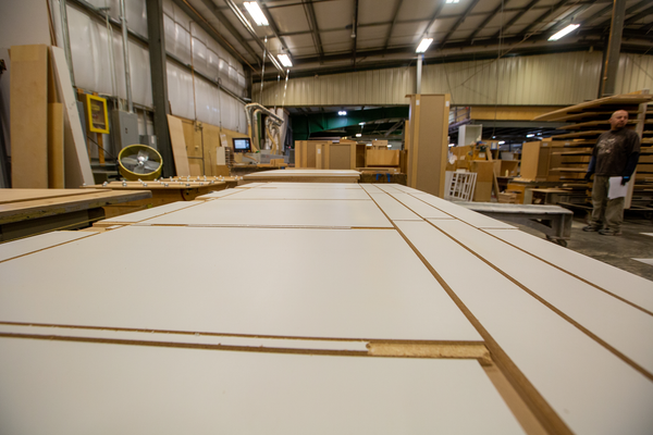 Image of white cabinets being held down by vacuum pressure on a hold down table while being cut.