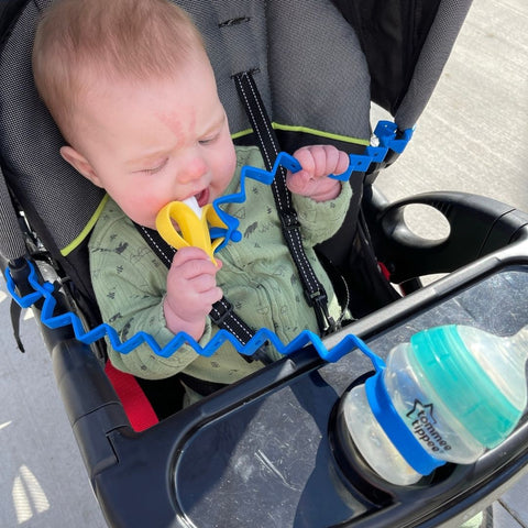 Baby in stroller with Busy Baby bottle bungee and Toy Bungee