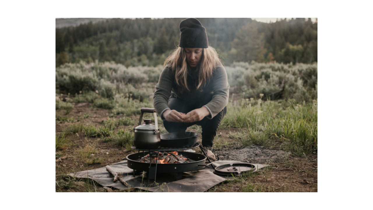 Women cooking breakfast in the wilderness over a fire pit