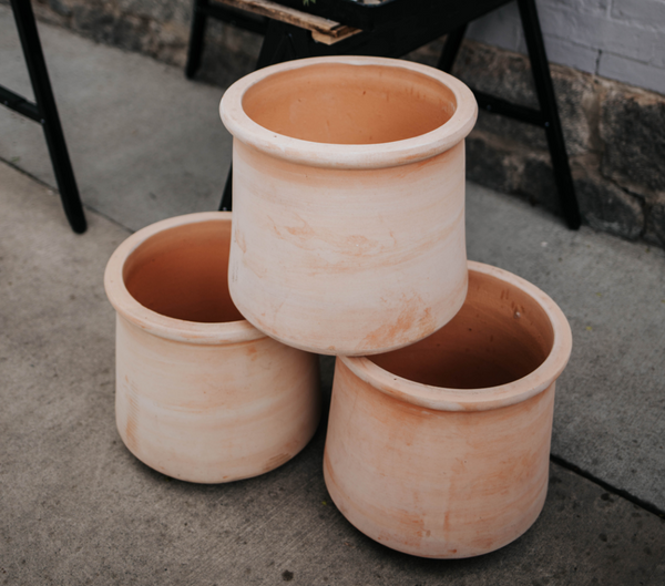 Salmon colored pots stacked and ready to be filled with soil