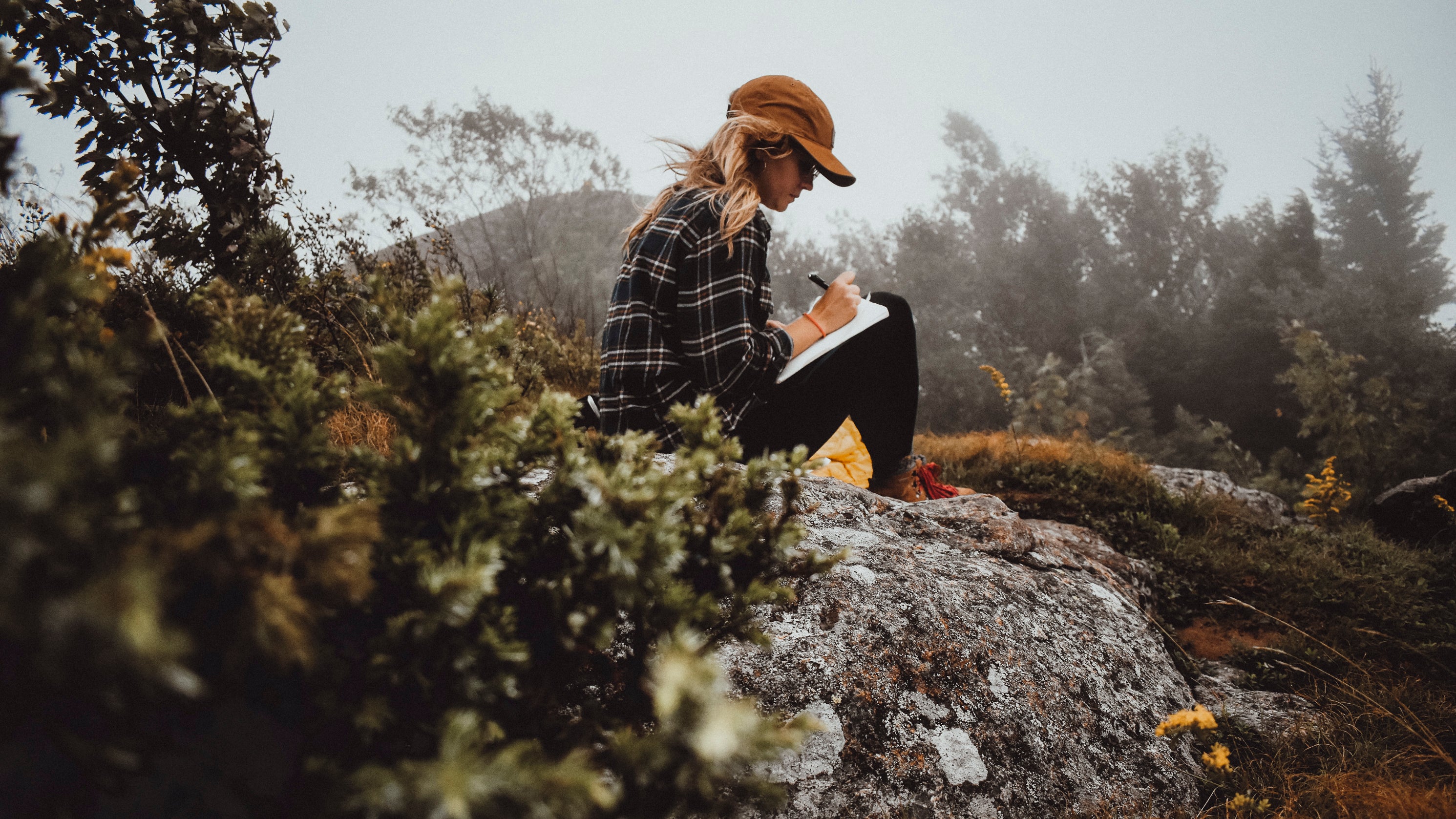 Person journaling in the mountains with overcast background