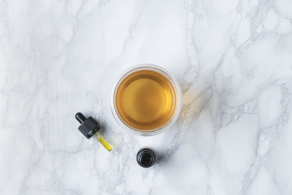 A cup of tea next to a CBD oil droppler