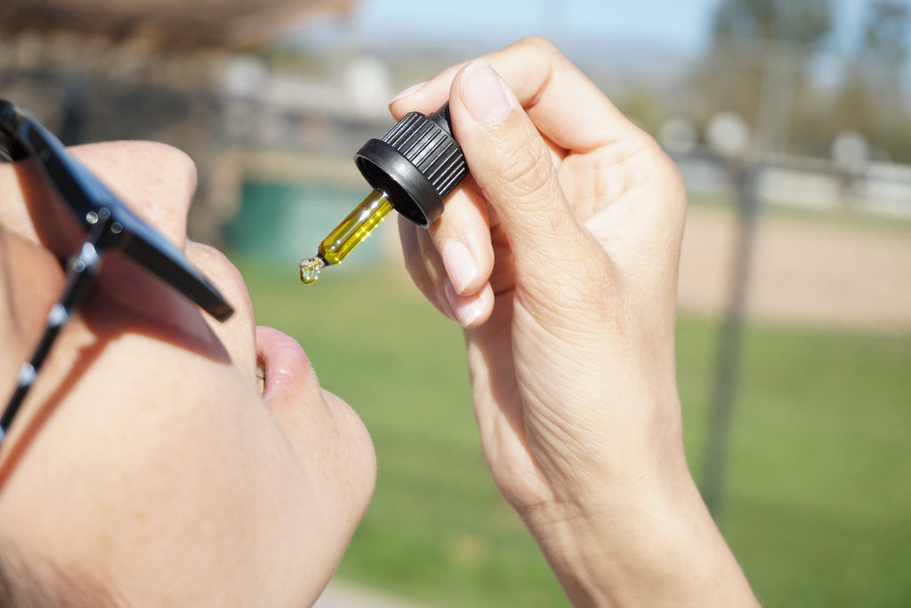 A woman taking CBD oil from a droppler
