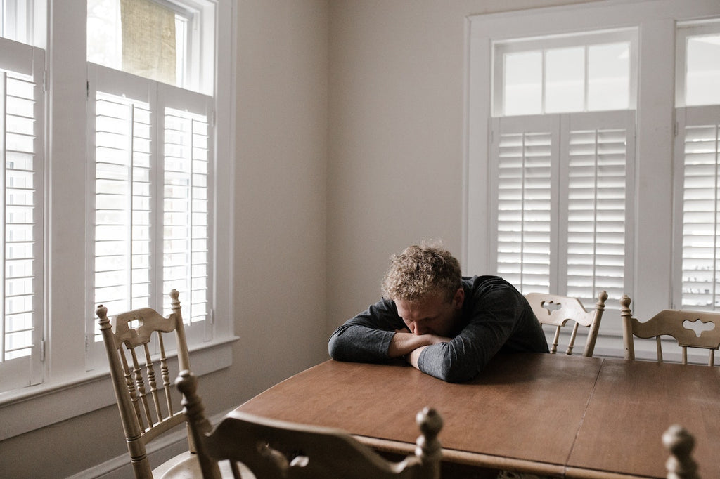 A man with anxiety sitting with his head down