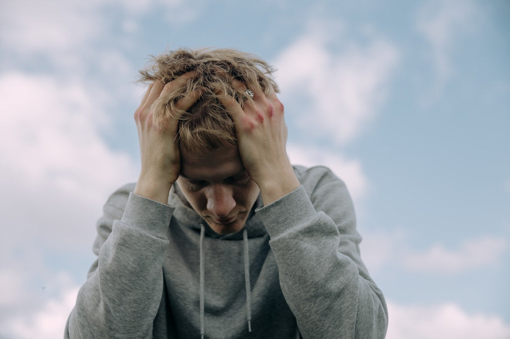 A man in a grey hoodie holding on to his head