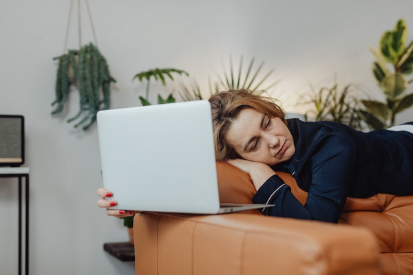 A stressed woman sleeping on an orange couch