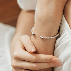 Close-up photo of Close By Me Jewelry's Sterling Silver Cable Cuff Cremation Bracelet on a woman's wrist.