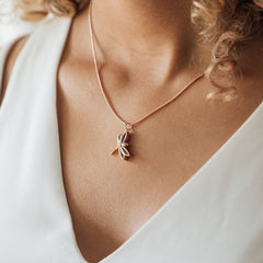 A close-up, cropped photo of Close By Me's Dragonfly Cremation Necklace in 14K Rose Gold being worn by a young woman.
