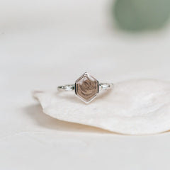 Close By Me Jewelry's 14K White Gold Hexagon White Baguette Diamond Band Cremation Ring resting on the edge of a white shell.