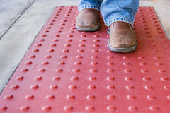 Person walking on red truncated domes