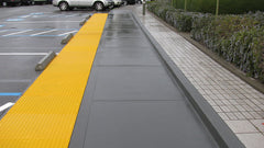 long line of yellow truncated domes between parking lot and sidewalk