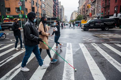 woman assists blind man in crosswalk