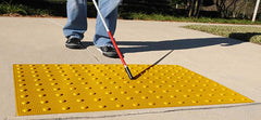 Blind person using cane on yellow truncated domes
