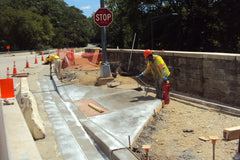Workers installing cast-in-place style truncated domes in new concrete sidewalk curb