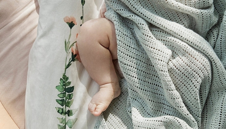 En miljöbild på en baby som ligger på en skötbädd. Endast ena benet syns.