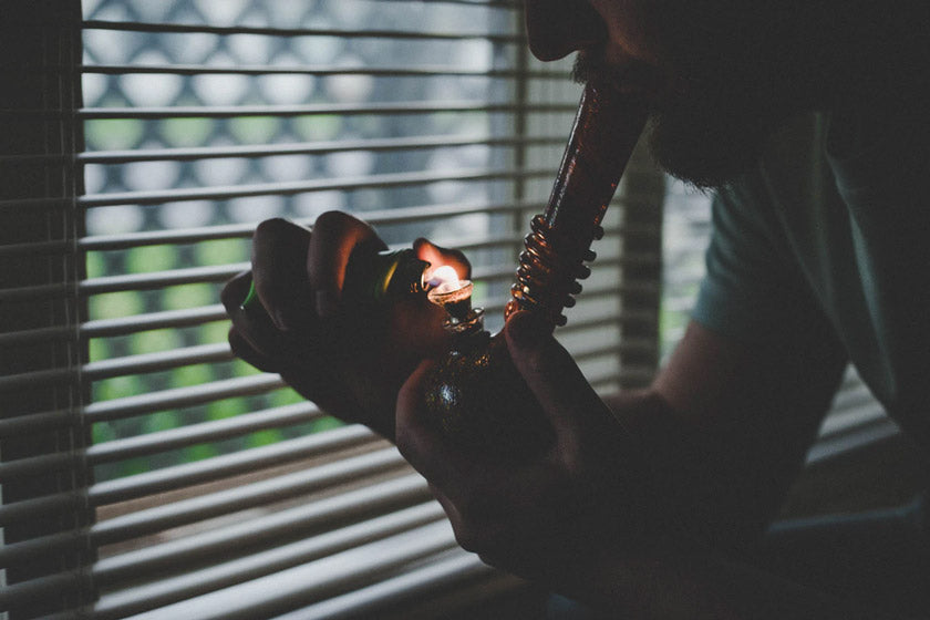 Man using a lighter and smoking from a bong