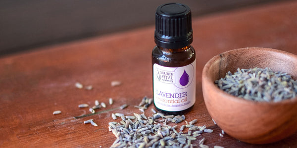 Lavender Essential Oil Bottle next to bowl of dried lavender buds