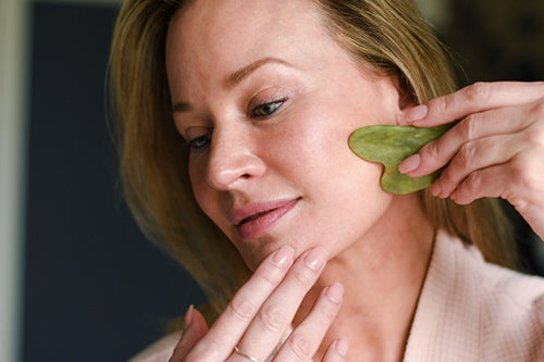 woman using jade gua sha on face