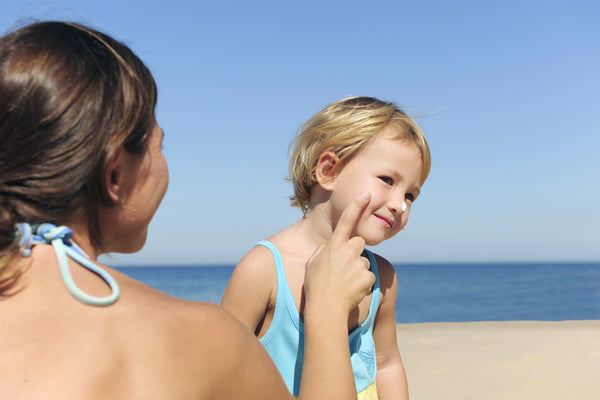 Woman at the beach applying sunscreen to her child's face