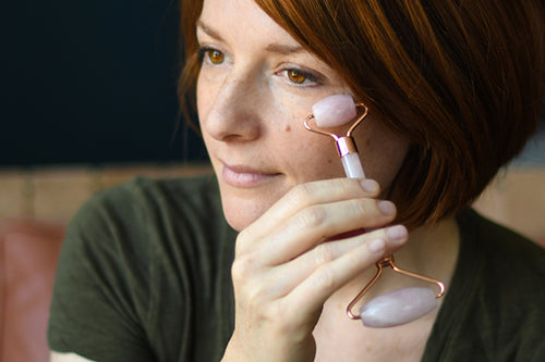Woman using rose quartz facial roller on face
