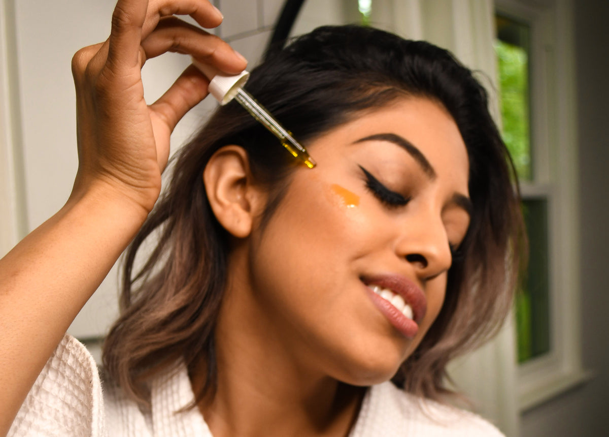 Woman drops botanical oil on her cheek