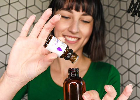 Woman diluting essential oil into amber bottle