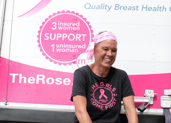 Breast cancer survivor standing in front of The Rose truck