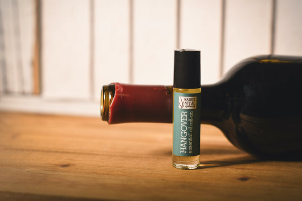 Source Vital Hangover Essential Oil Roll-On in front of wine bottle on its side