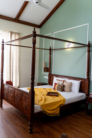 4-poster bed with carved headboard and footboard against green wall with white wainscotting