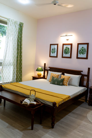 Bedroom with solid wood bed, bench near footboard, 3 paintings of foliage with wooden frame