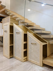 Storage zone under the staircase with 3 pull-out trolley cabinets of varying heights, sizes and shelves
