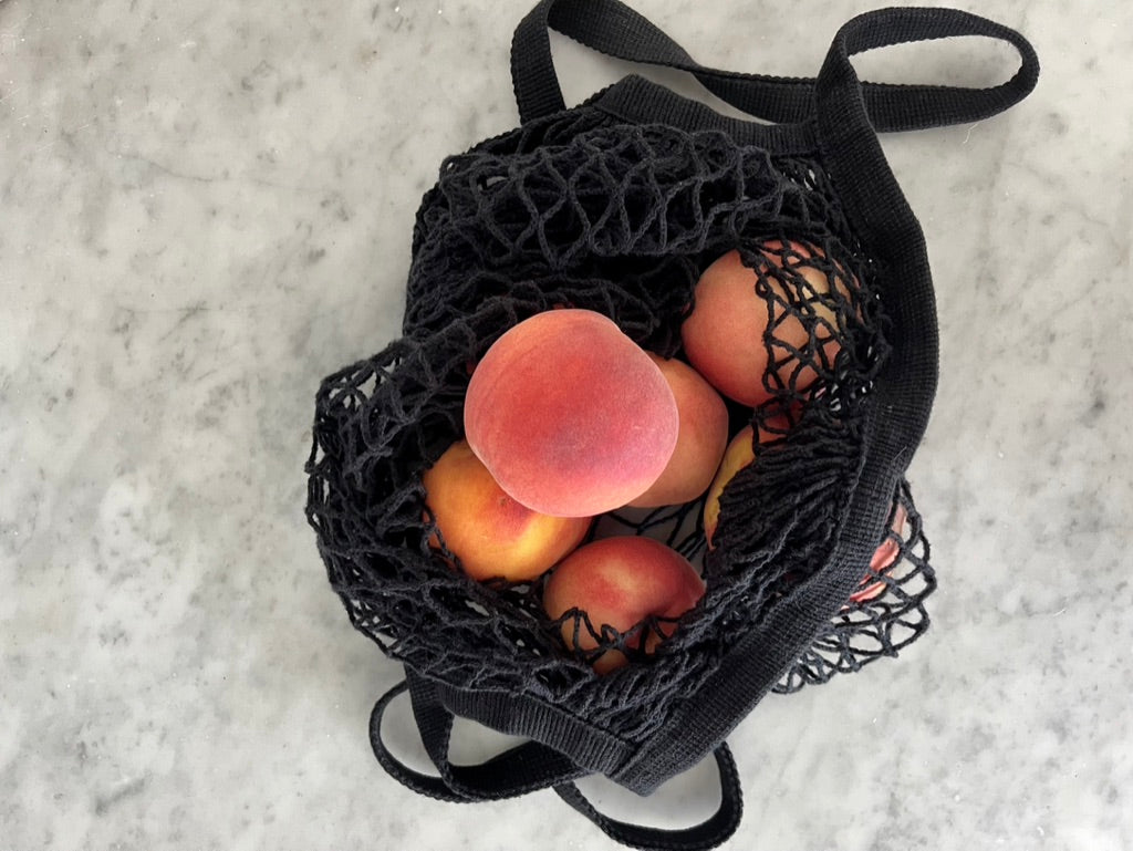 Peaches in black string tote bag