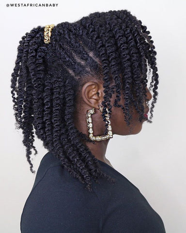 A Black woman wearing a twist-out in a half-up, half-down hairstyle with gold earrings