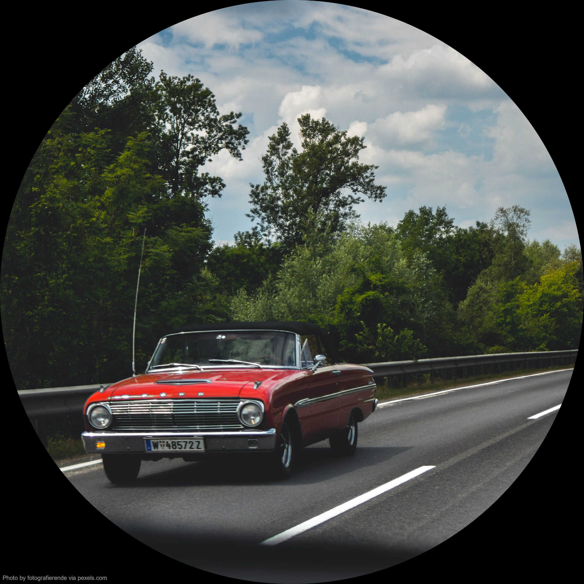 Ein rotes Cabriolet fährt eine Landstrasse entlang.