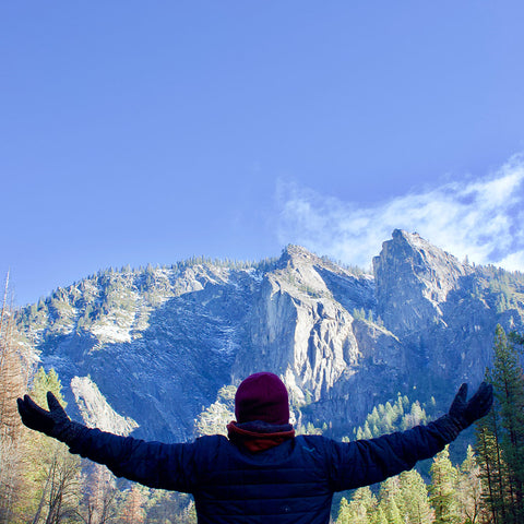 A person with their arms outstretched towards the mountains. 