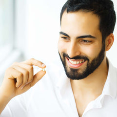 A handsome young man holding a zinc pill and smiling.