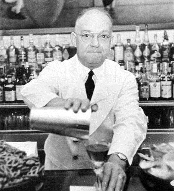 Black and white photo of Fernand Petiot, the creator of the Bloody Mary cocktail, serving drinks behind a bar.
