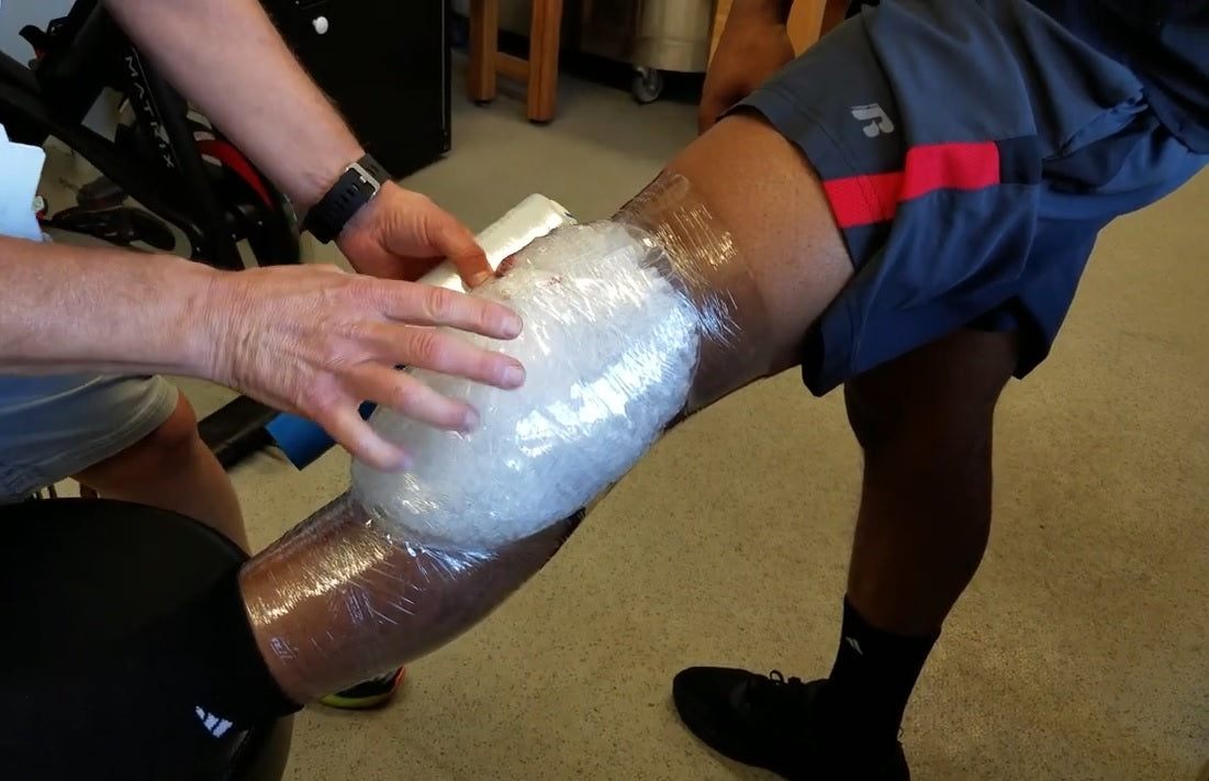 Sports trainer wrapping ice on a basketball player's knee